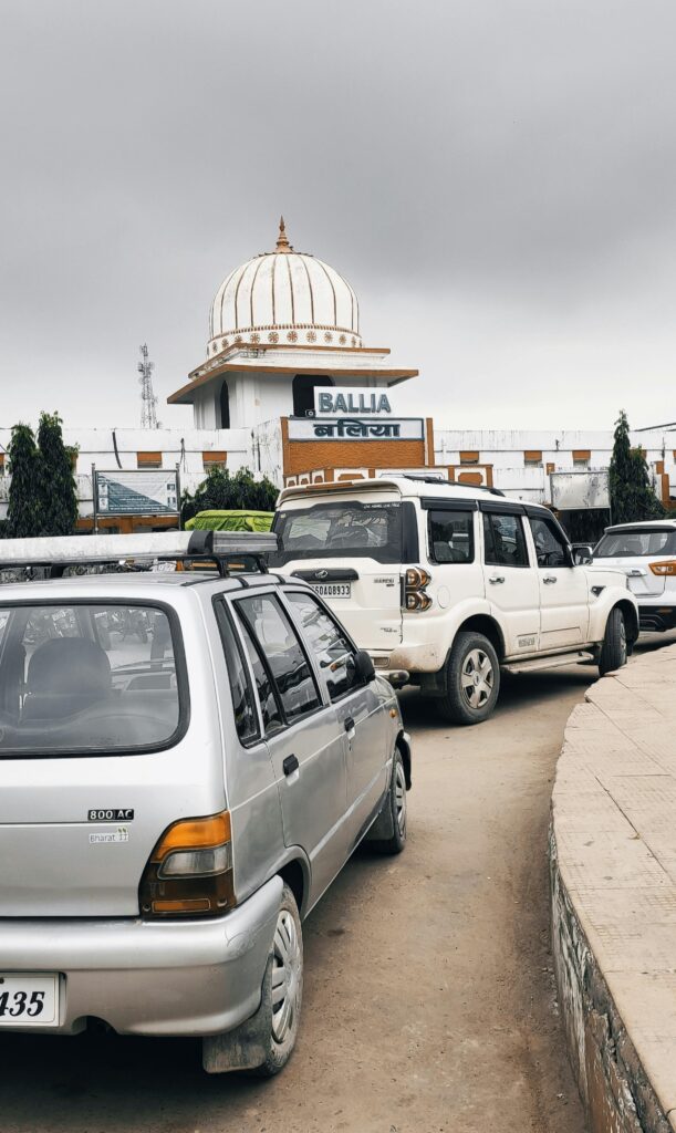 Vehicles lined up near Ballia railway station under a cloudy sky, showing daily transportation.
